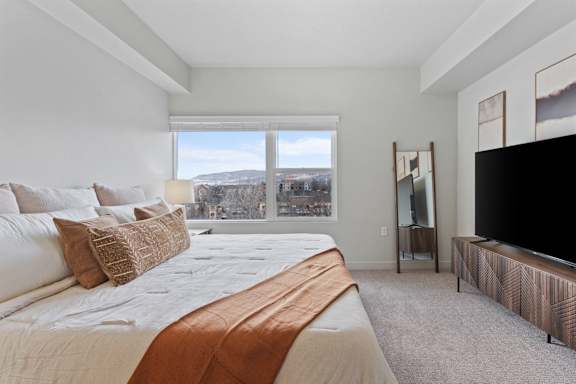 A bedroom with a large bed and a flat screen TV. at Wilmington Flats Apartments, Salt Lake City, UT, 84106