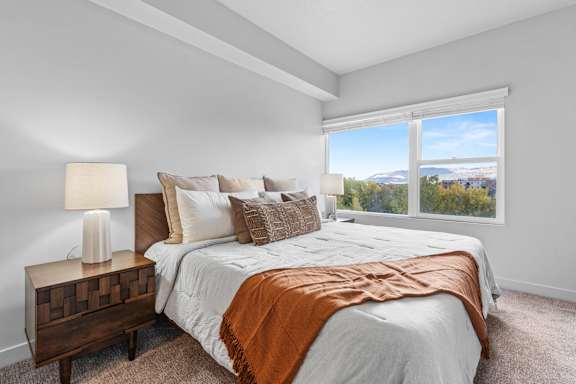 A bedroom with a large bed and a view of the city through the window. at Wilmington Flats Apartments, Utah