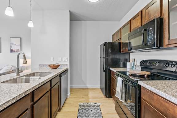 A modern kitchen with dark wood cabinets and black appliances. at Wilmington Flats Apartments, Salt Lake City, UT, 84106