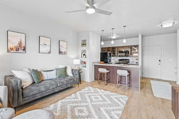 A living room with a grey couch and a bar area. at Wilmington Flats Apartments, Utah, 84106