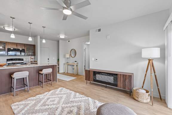 A modern kitchen with a bar area and a living room with a fireplace. at Wilmington Flats Apartments, Salt Lake City