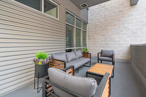 A patio with grey couches and a wooden table. at Wilmington Flats Apartments, Salt Lake City