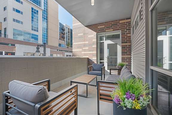 A patio with a table and chairs and a planter with flowers.Q at Wilmington Flats Apartments, Salt Lake City