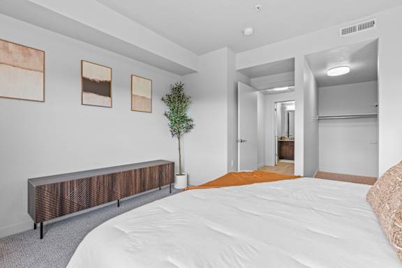 A bedroom with a bed, a bench, and pictures on the wall. at Wilmington Flats Apartments, Utah