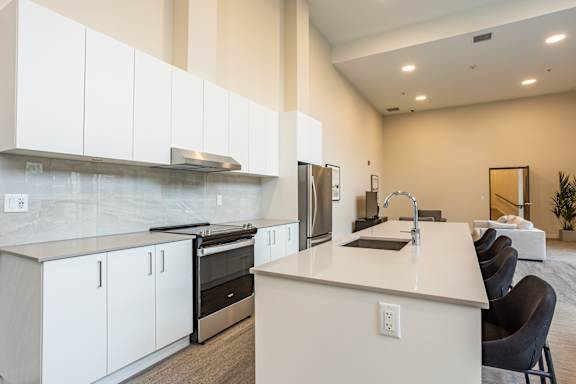 A modern kitchen with white cabinets and a marble backsplash.