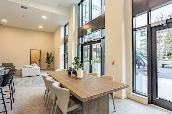 A conference room with a long table and chairs, a plant, and a framed picture on the wall.