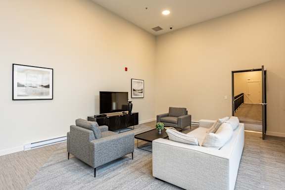 A living room with a grey couch, a black coffee table, and a white sofa.