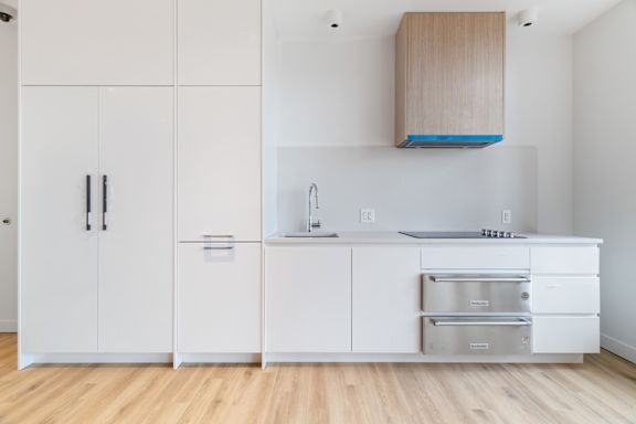 A kitchen with white cabinets and a wooden hood.