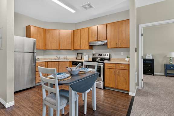 A kitchen with a table and chairs in front of a refrigerator.