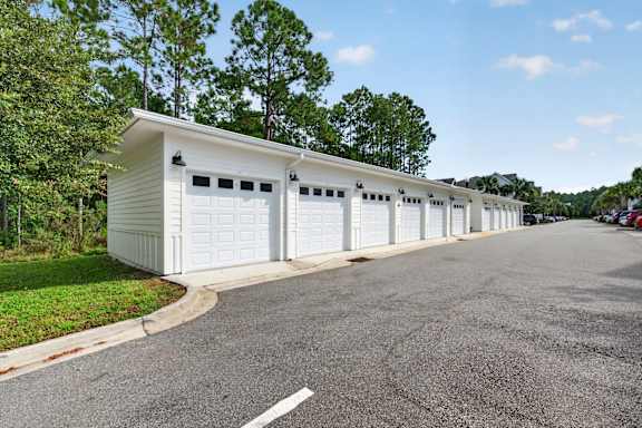 A row of white garage doors are lined up on the side of a road.