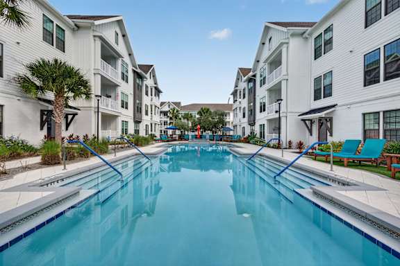A long rectangular swimming pool in front of apartment buildings.