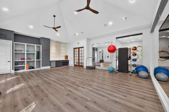 A spacious room with a wooden floor and a ceiling fan.
