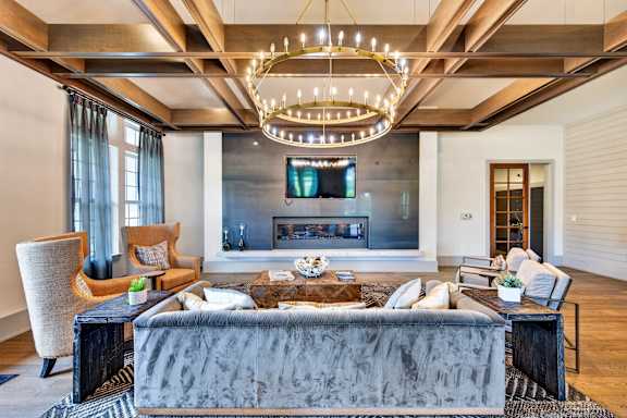 A modern living room with a grey sofa and a chandelier.