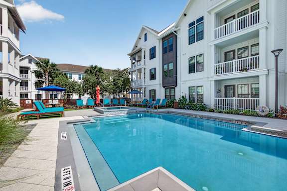 A swimming pool in front of a white building.