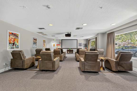 A room with grey carpet and brown chairs.
