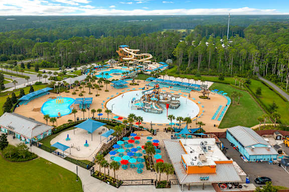 An aerial view of a water park with a large pool and a smaller pool with a slide.