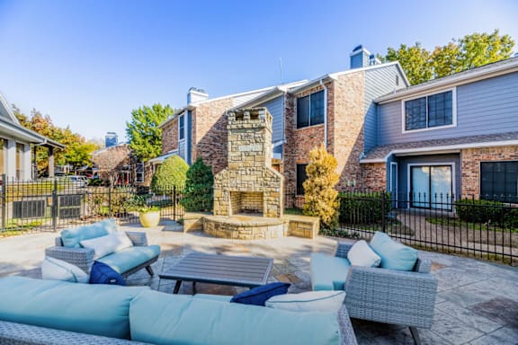 A patio with a fireplace and couches in front of a house.