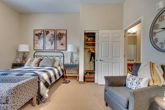 A bedroom with a bed, a couch, and a clock on the wall.