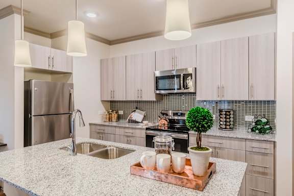 A kitchen with a granite countertop and a refrigerator at Atlas Point at Prestonwood Apartments , Texas