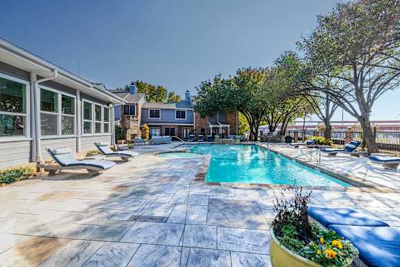 A pool surrounded by a patio and trees. at Avalon Villas Apartments , Texas, 75062