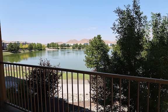 A view of a lake from a balcony with a car parked on the left.