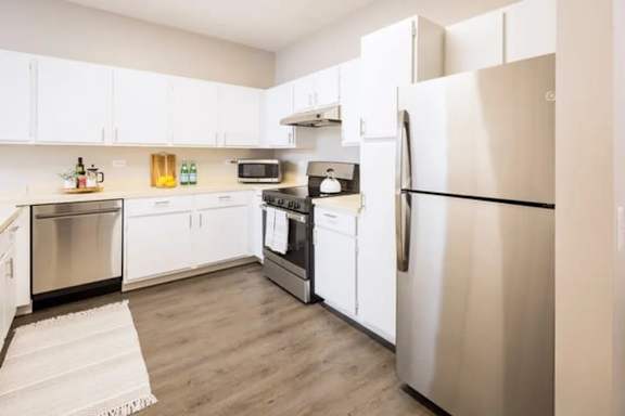 A kitchen with white cabinets and a stainless steel refrigerator.