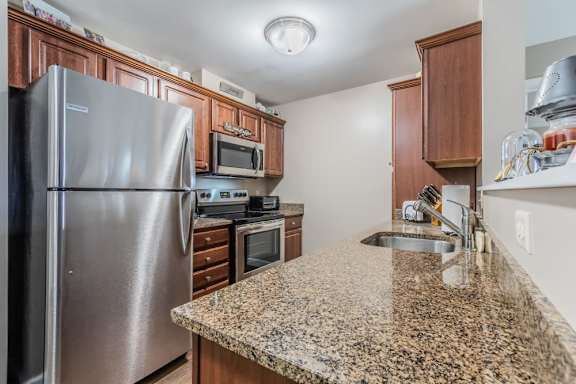 Modern kitchen with granite countertops and stainless appliances at Schuyler Commons Apartments, Utica