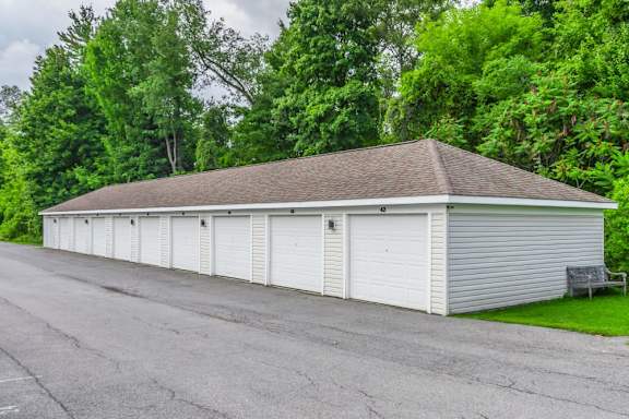 White storage unit building with multiple garage doors at Schuyler Commons Apartments, Utica, 13502