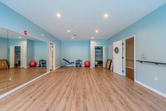 Fitness studio with exercise equipment and mirrors at Glenmont Abbey Village, 55+ Apartments, Glenmont