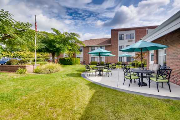 A patio with a table and chairs is surrounded by a grassy area. at King City Senior Village Apartments, King City, OR, 97224