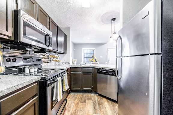 A modern kitchen with stainless steel appliances and wooden cabinets. at Avalon Villas Apartments , Texas, 75062