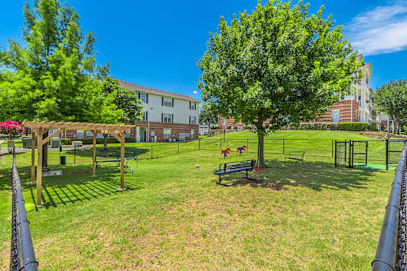 A park with a bench and a tree in the foreground. at The Spring at Silverton Apartments, Fort Worth, 76133
