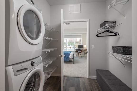 A laundry room with a washer and dryer on the left and a small living area with a couch and chair on the right.