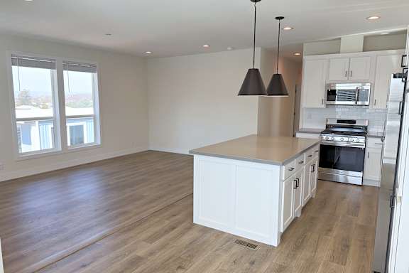 A kitchen with white cabinets and a wooden floor.