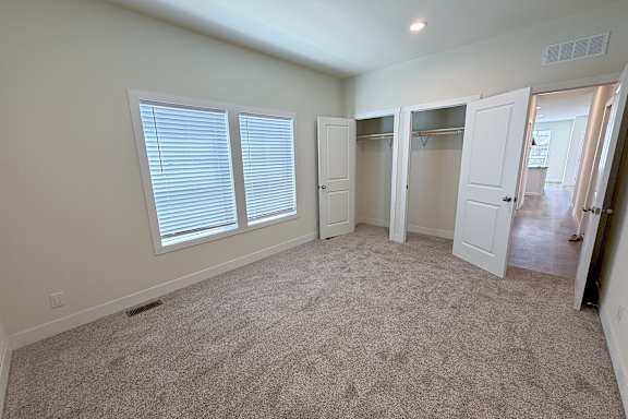 A room with carpeted floor, white walls, and a window with blinds.