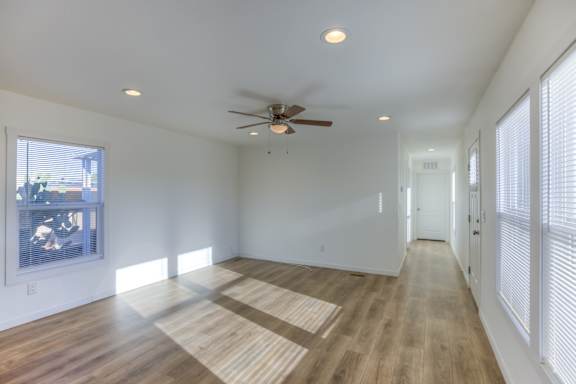 A room with a ceiling fan and wooden flooring.