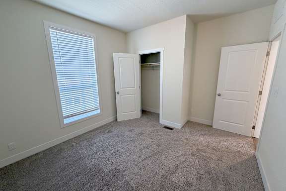 A room with a carpeted floor and two doors, one of which is open.