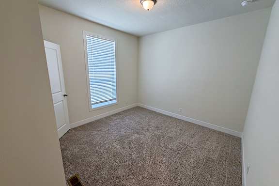 A room with a carpeted floor and a window with blinds.