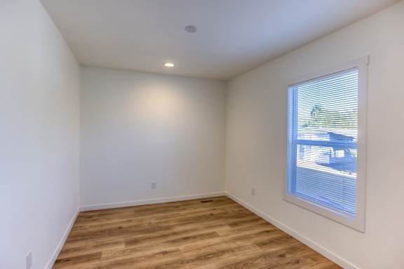 A room with wooden floors and a window showing a view of a street.