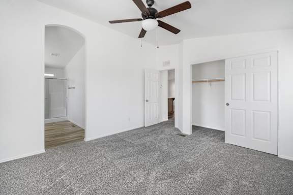 A room with a ceiling fan and carpeted floor.