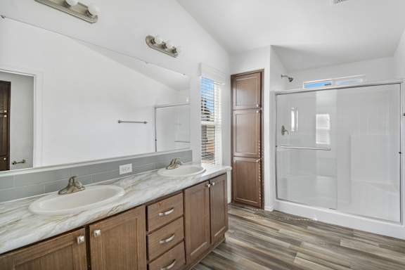 A bathroom with two sinks and a walk-in shower.