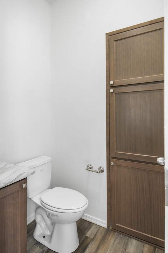 A white toilet sits next to a wooden door in a bathroom.