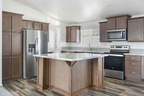 A kitchen with a refrigerator, microwave, oven, and sink.