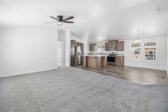 A spacious living room with a kitchen in the background.