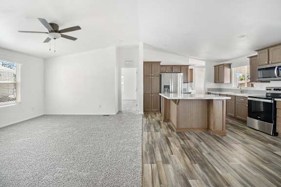A spacious kitchen and living room with wood flooring and white walls.