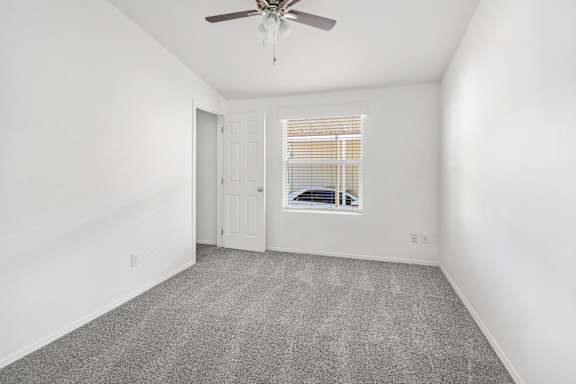 A room with a ceiling fan and a window with blinds.