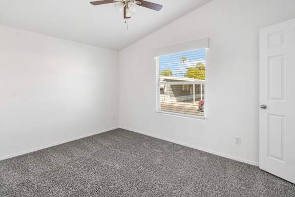 A room with a ceiling fan and a window with blinds.