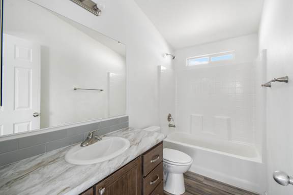 A white bathroom with a marble countertop and a white toilet.