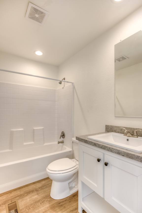 A white toilet sits in a bathroom with a white tub and sink.