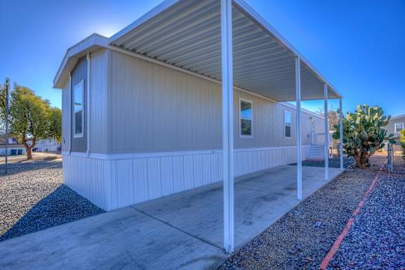 A small white building with a metal roof and a gravel driveway in front.